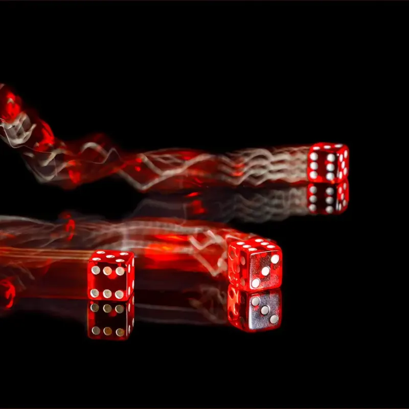 Three red dice bouncing with red light trails on black